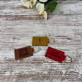 Three personalized leatherette keychains on a wooden surface 
